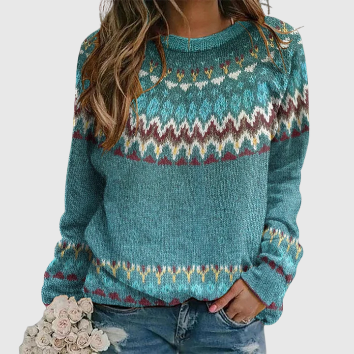 A woman wearing a teal jumper with a colourful retro zigzag pattern and a round neck, relaxed and cosy for autumn.