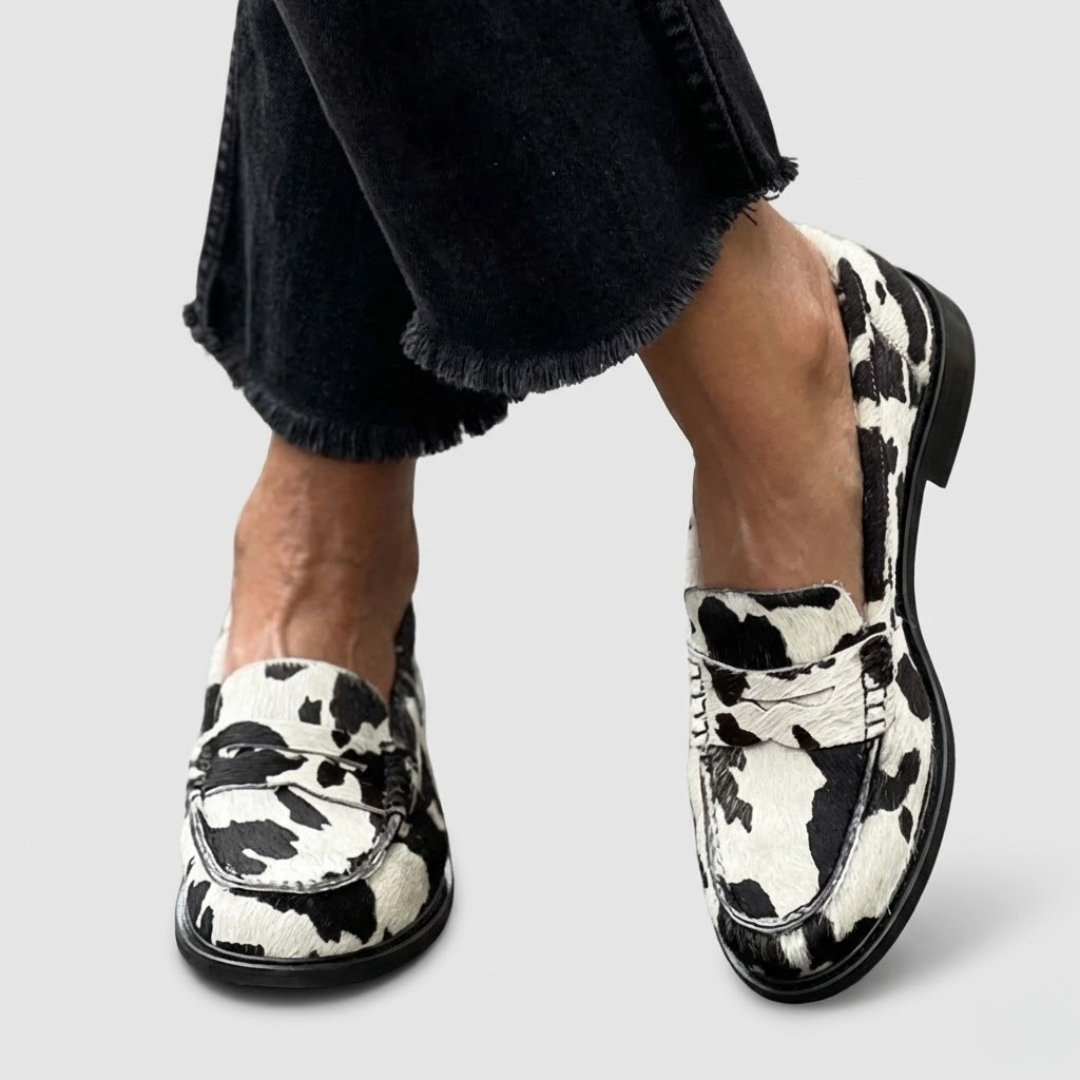 A woman wearing striking zebra-print loafers with tailored trousers, standing confidently.