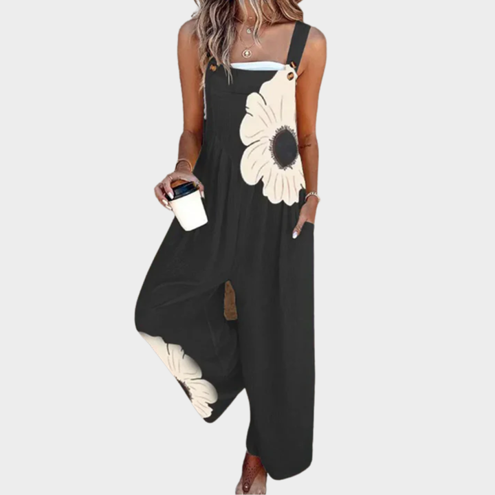 A woman wearing elegant black dungarees with a single large cream bloom and adjustable straps.