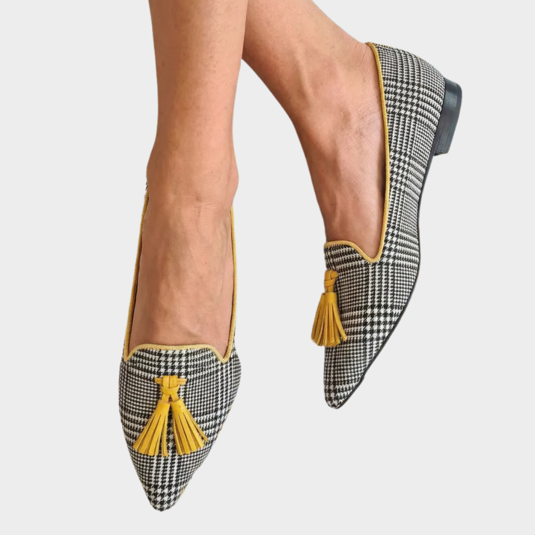 A woman wearing bright yellow check loafers with tailored trousers, looking cheerful and pulled together.