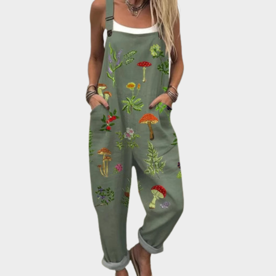 Woman wearing olive green dungarees with a botanical mushroom and fern print, adjustable straps, cheerful and relaxed.