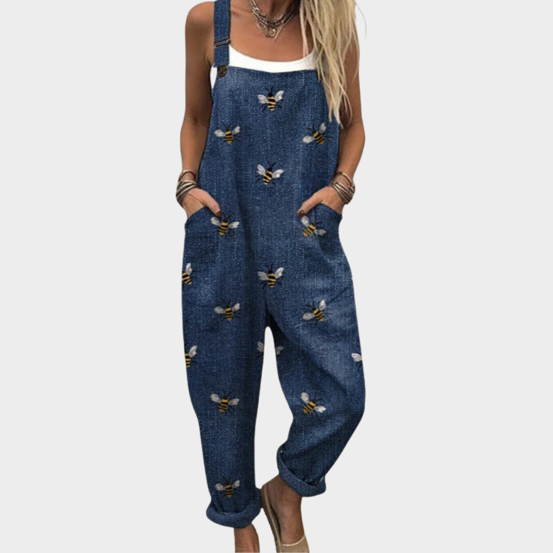 Woman wearing navy dungarees with a scattered golden bee print, adjustable straps, cheerful and relaxed.