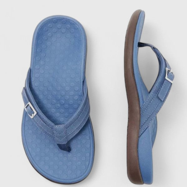 A woman in light blue lightweight flip-flops relaxing on a sunny terrace, feet light and comfortable.