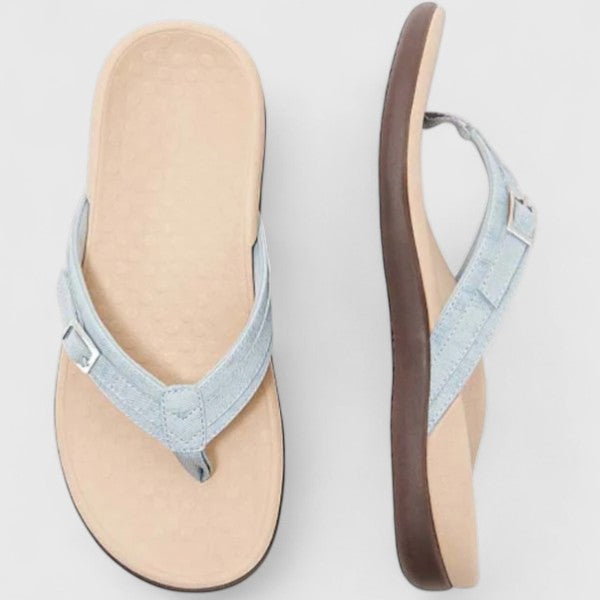 A woman in light blue lightweight flip-flops relaxing on a sunny terrace, feet light and comfortable.