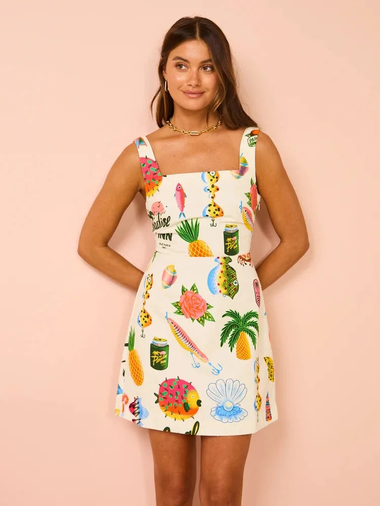Woman on holiday wearing the Stella tropical print dress with a square neckline, standing in the sunshine.