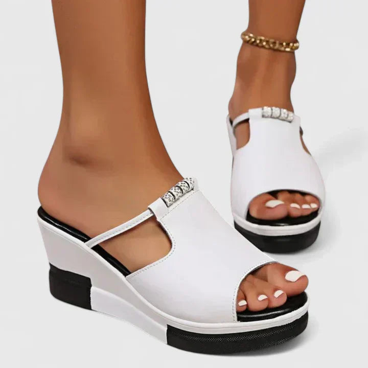 A woman standing confidently in white chic support sandals with a broad, cushioned base.