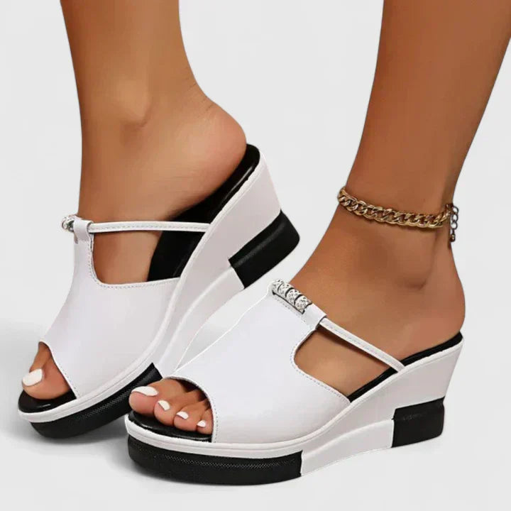 Black and white platform wedge mules with an open toe and a cut-out band across the front.