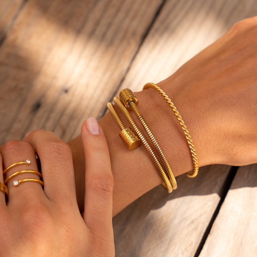 Twisted gold bracelet in gold and silver tones on a plain background