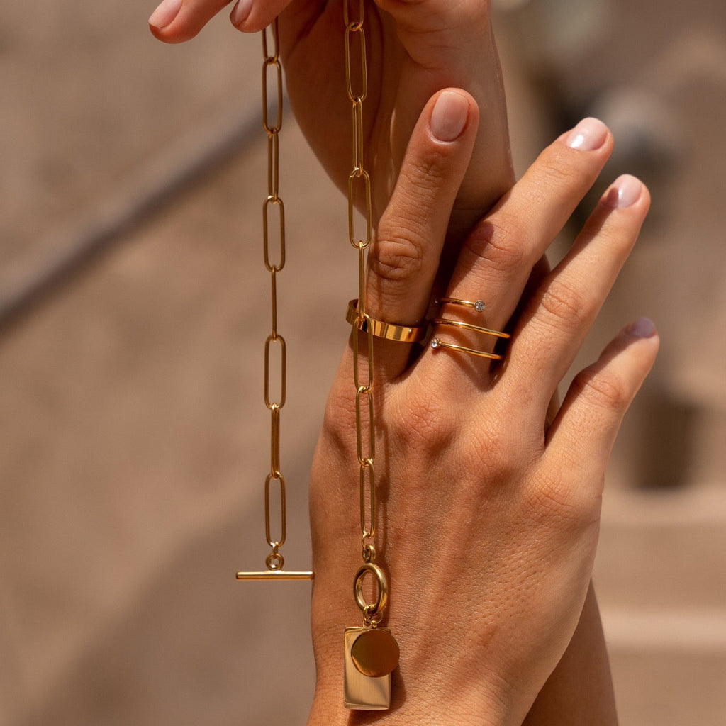 Gold chain necklace with a sleek rectangular clasp on a plain background