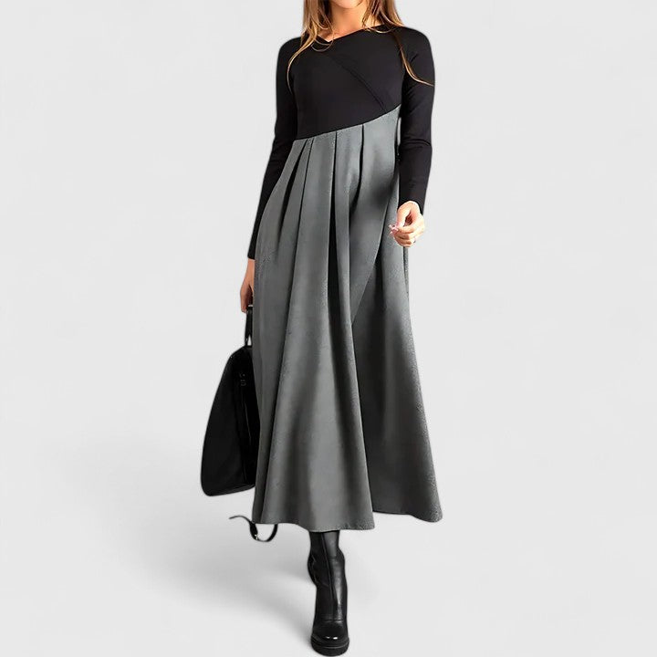 Woman wearing the Anna refined dress in black-grey, posing elegantly indoors.