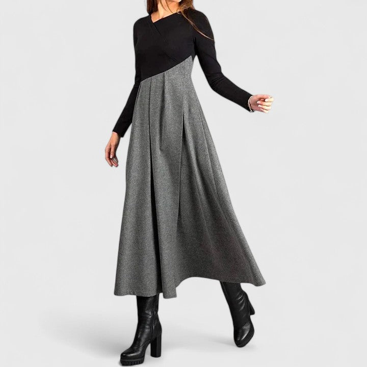 Woman wearing the Anna refined dress in black-grey, posing elegantly indoors.