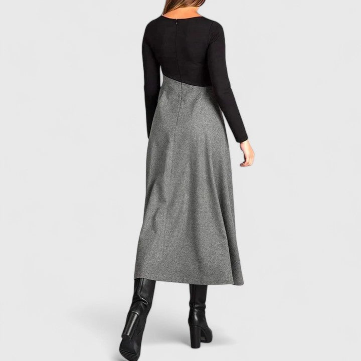 Woman wearing the Anna refined dress in black-grey, posing elegantly indoors.