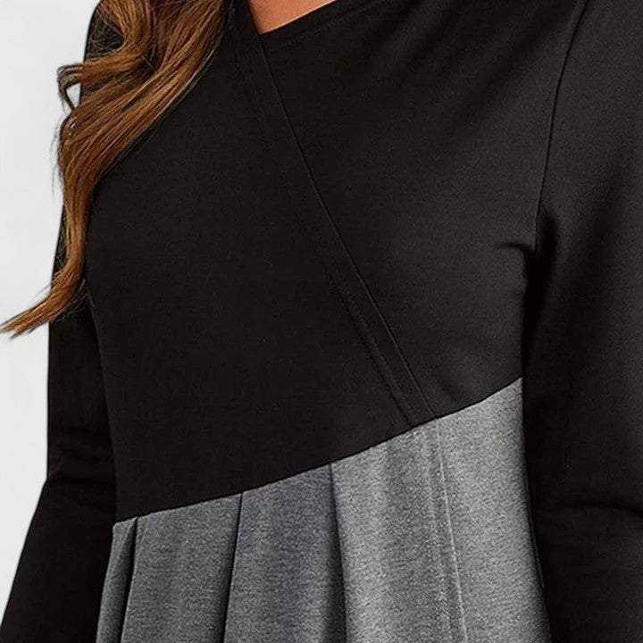 Woman wearing the Anna refined dress in black-grey, posing elegantly indoors.