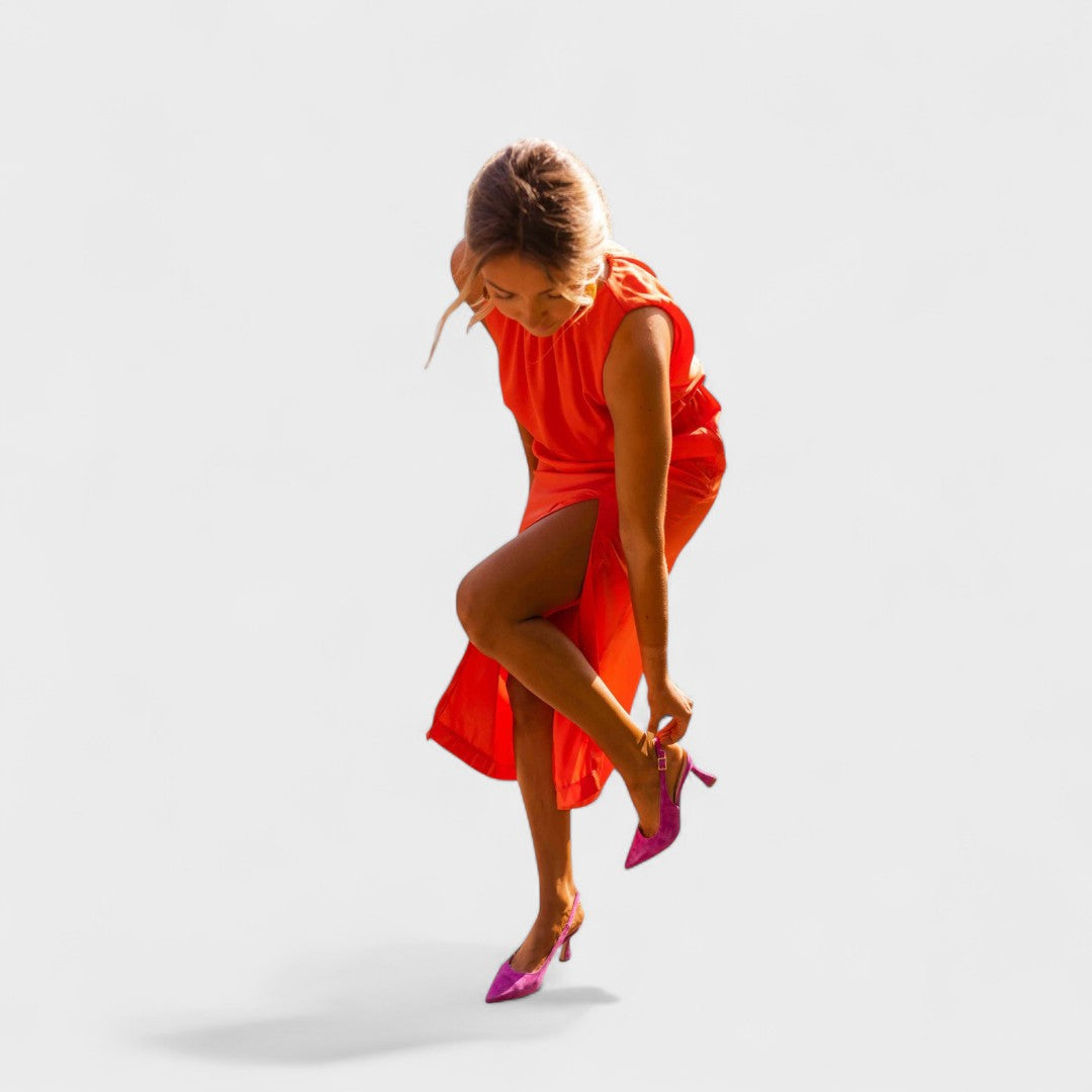 A vivid orange halter-neck fluid midi dress with a front split, styled for a bold summer occasion