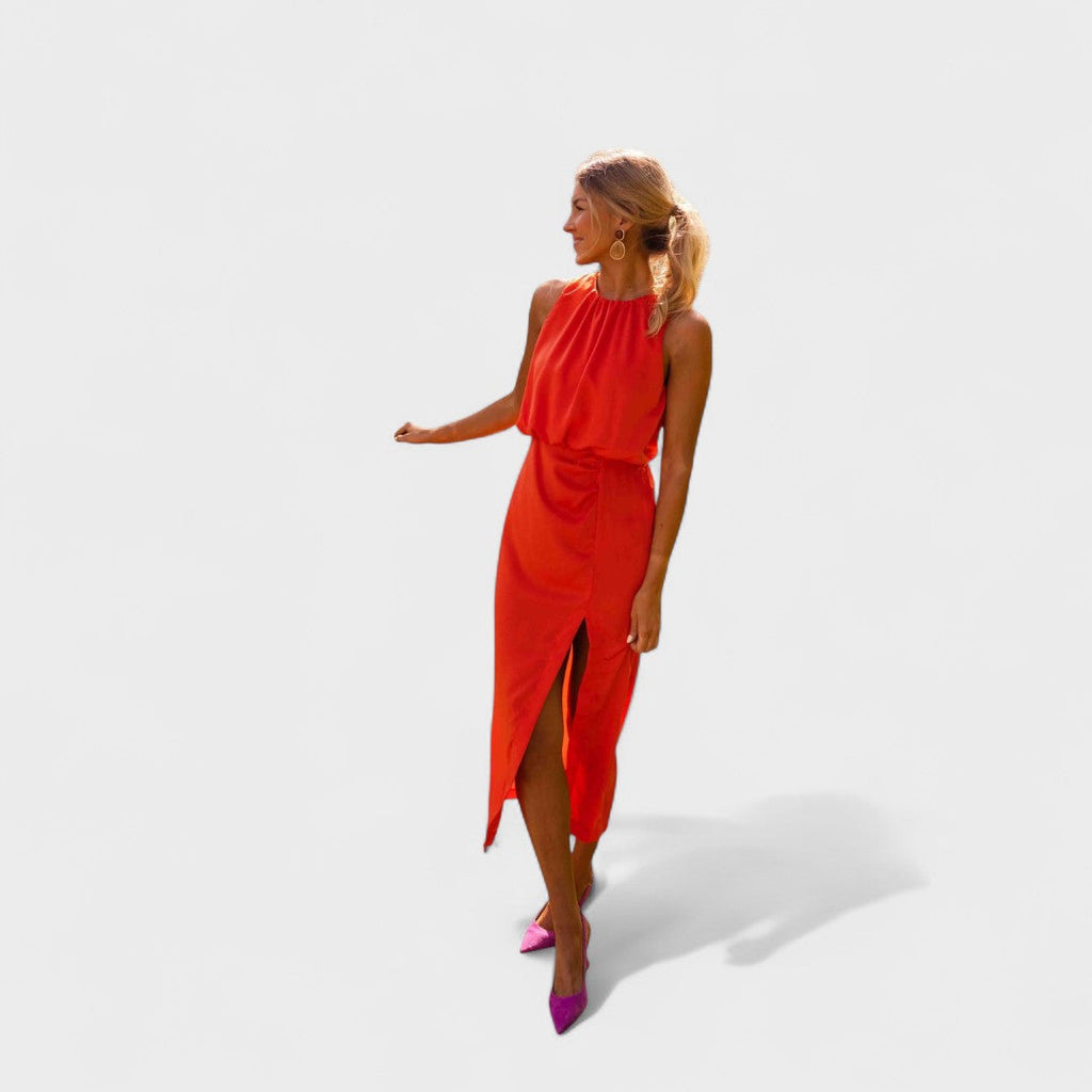 A vivid orange halter-neck fluid midi dress with a front split, styled for a bold summer occasion