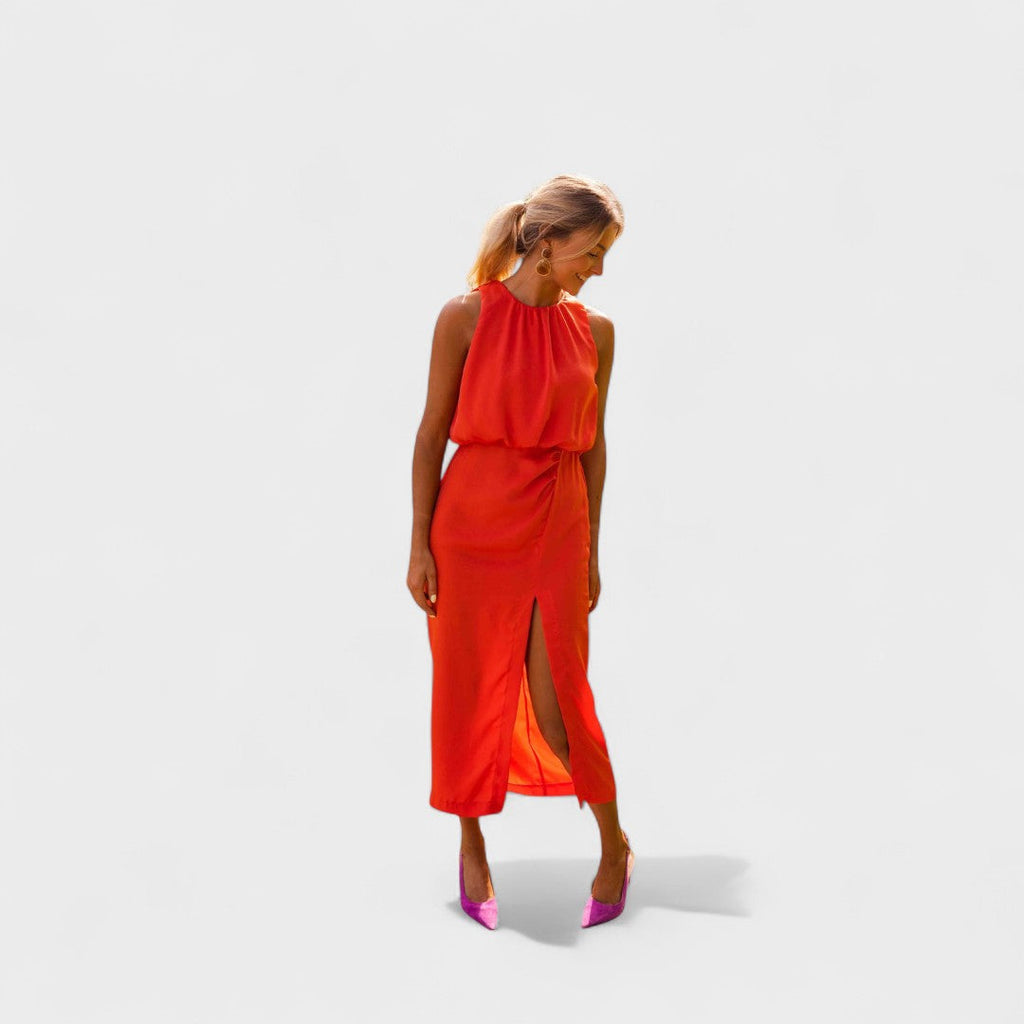 A vivid orange halter-neck fluid midi dress with a front split, styled for a bold summer occasion