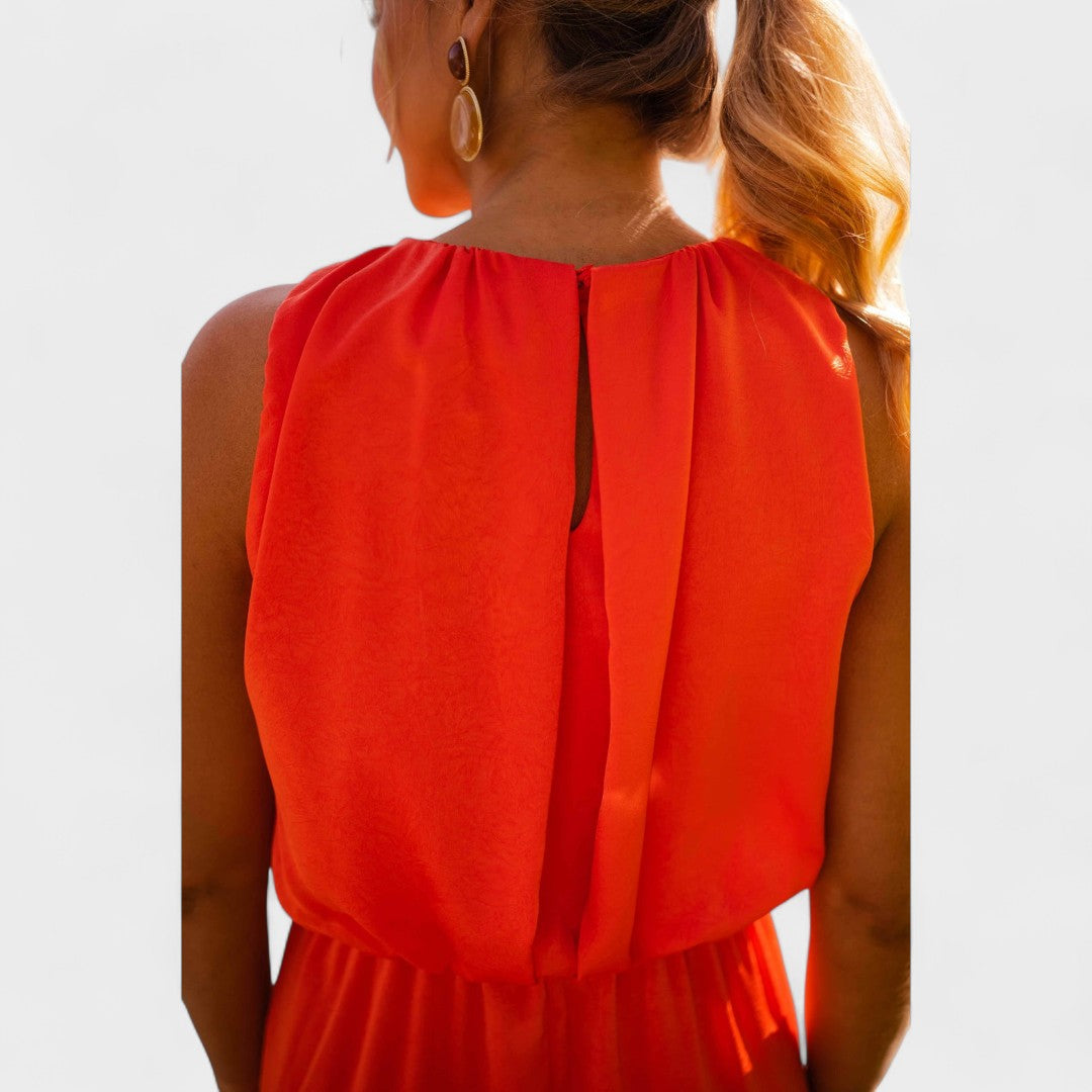 A vivid orange halter-neck fluid midi dress with a front split, styled for a bold summer occasion