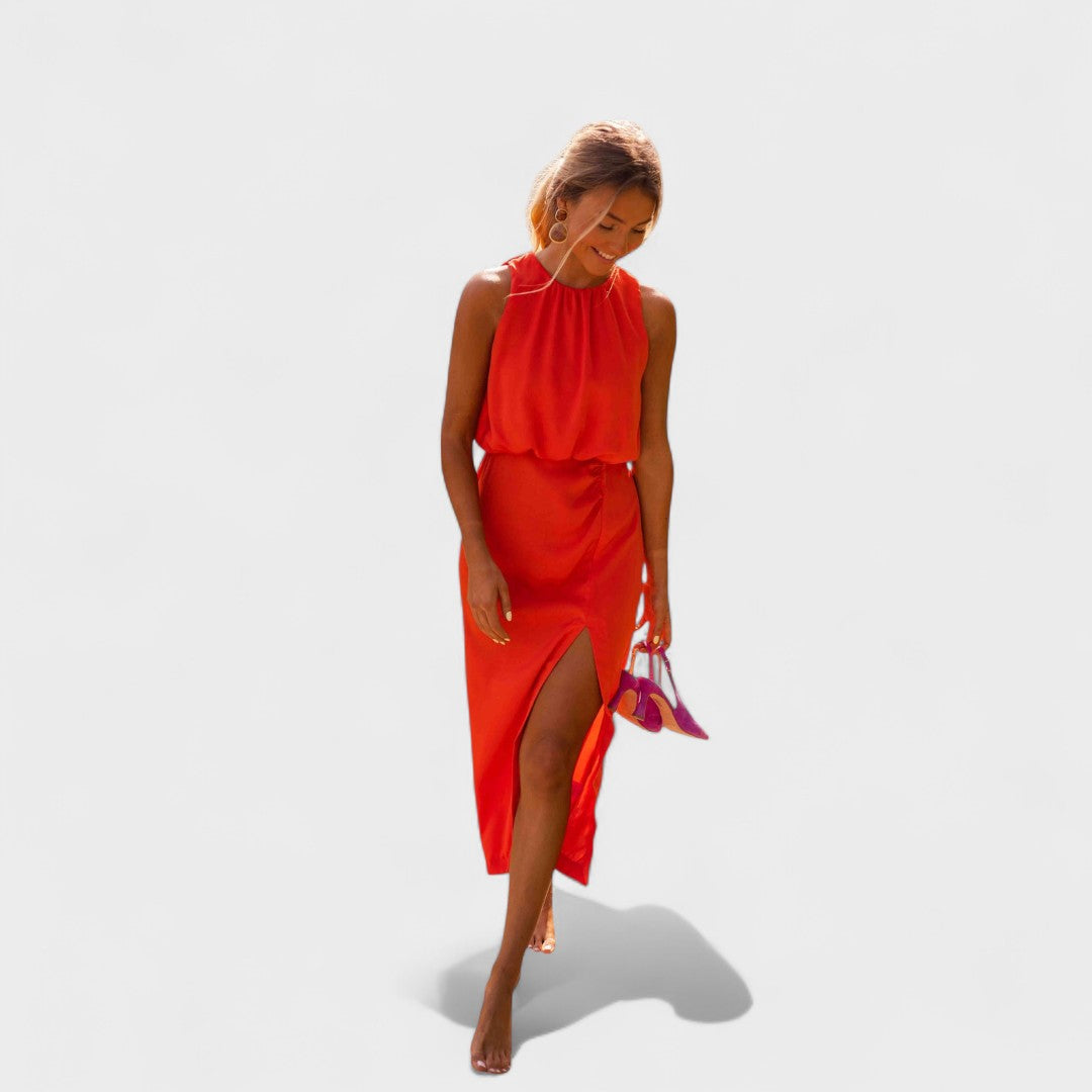 A vivid orange halter-neck fluid midi dress with a front split, styled for a bold summer occasion