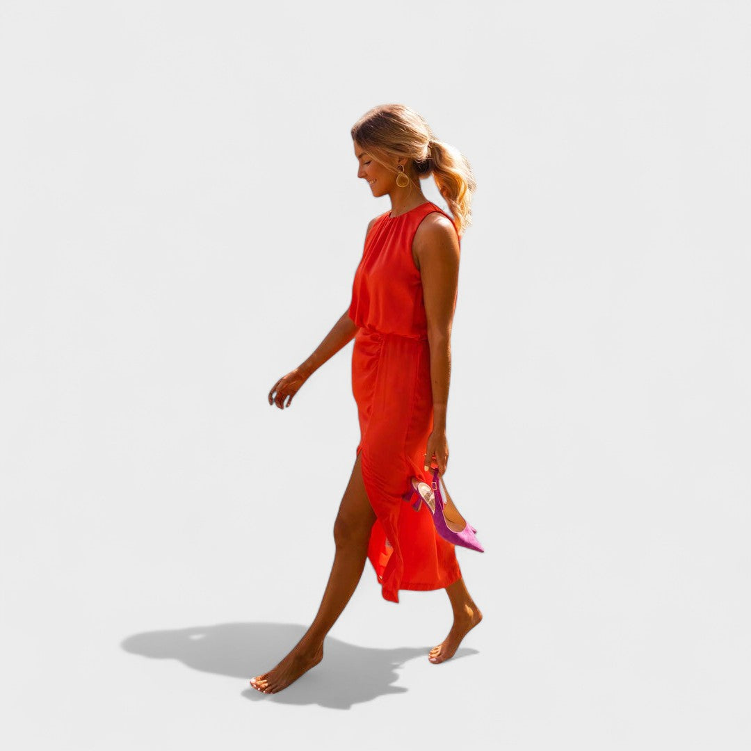 A vivid orange halter-neck fluid midi dress with a front split, styled for a bold summer occasion