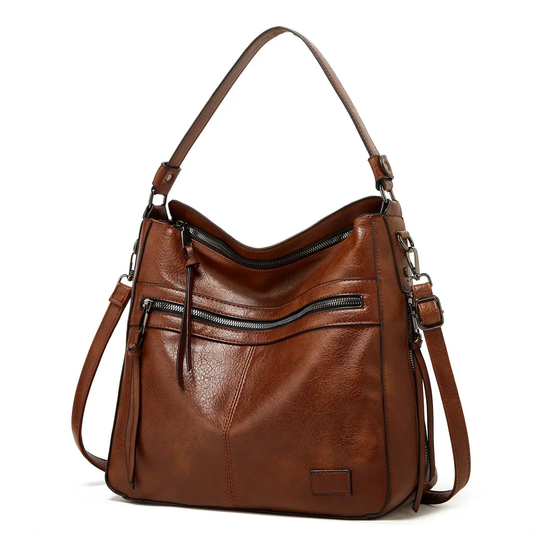 A woman carrying a structured brown everyday tote bag on her shoulder while out and about in town.