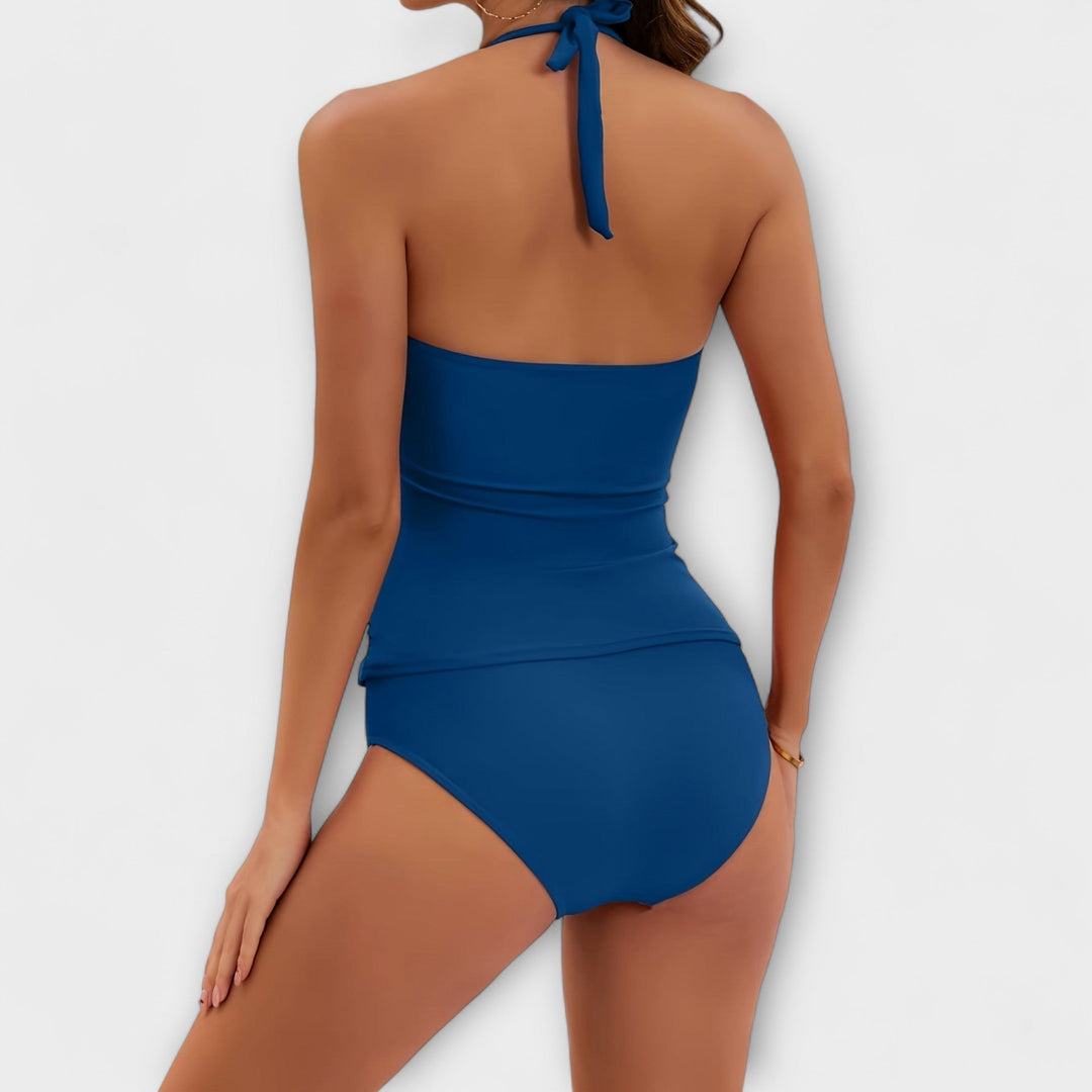 A woman by the water in a lively printed two-piece swimsuit, relaxed and confident in the sun.