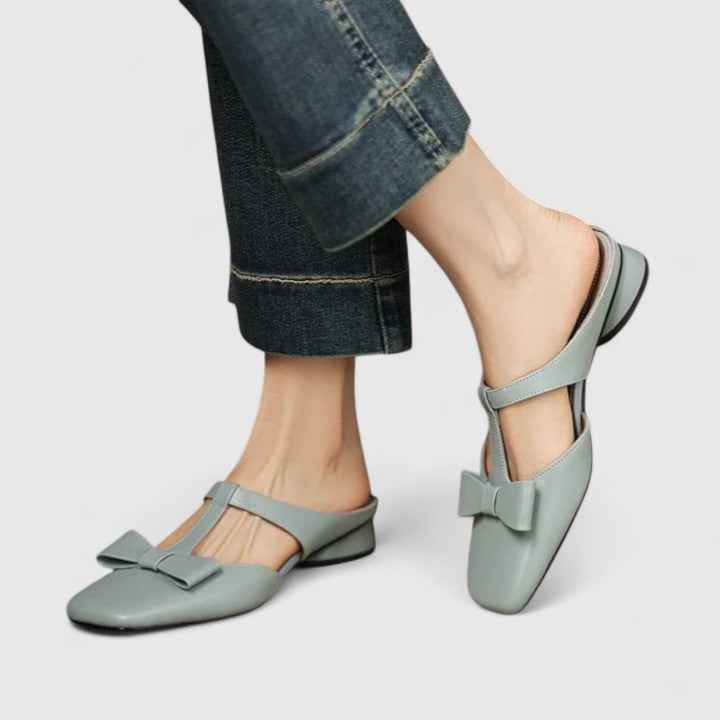 A woman wearing soft pink comfort sandals with a broad, cushioned footbed on a sunny day.