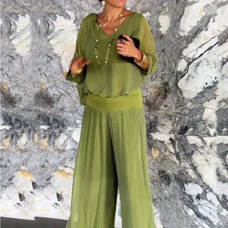 A woman wearing a flowing lounge two-piece set with a V-neck top and wide-leg trousers.