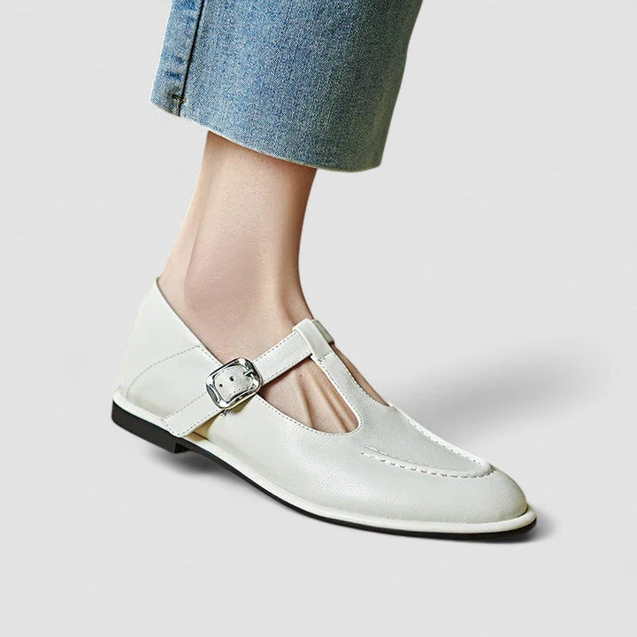 Woman wearing black low-heel Mary Jane shoes with a strap, stepping through a doorway.