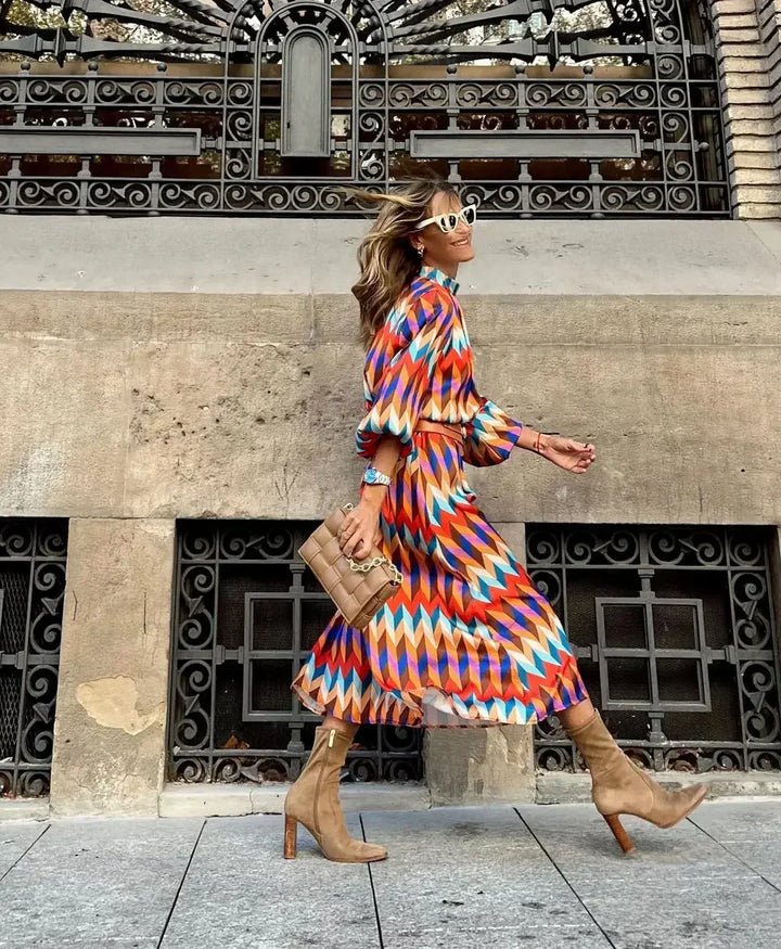 Woman in the Daisy geometric print maxi dress with a high neckline and puff sleeves, walking through a city street.