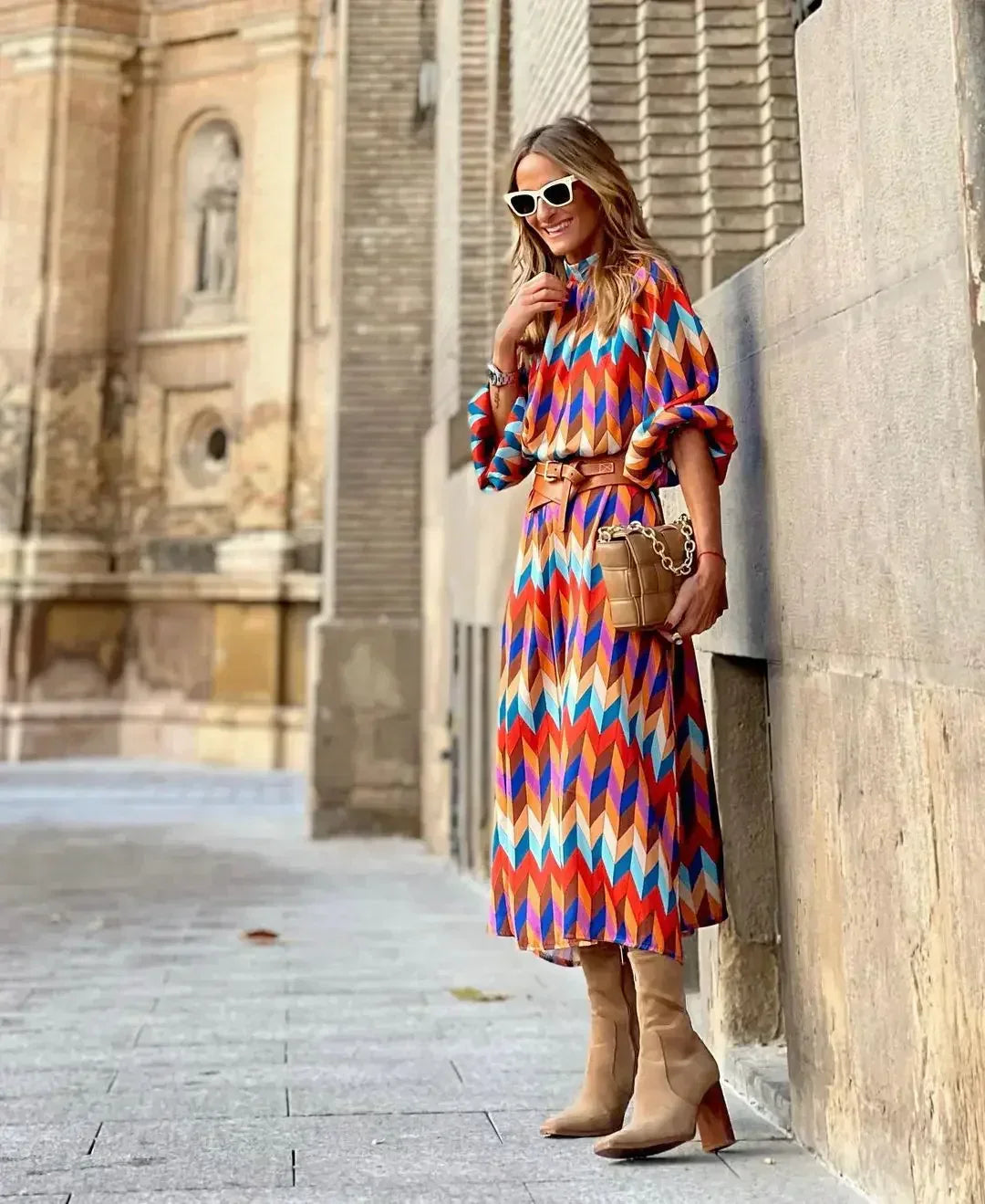 Woman in the Daisy geometric print maxi dress with a high neckline and puff sleeves, walking through a city street.