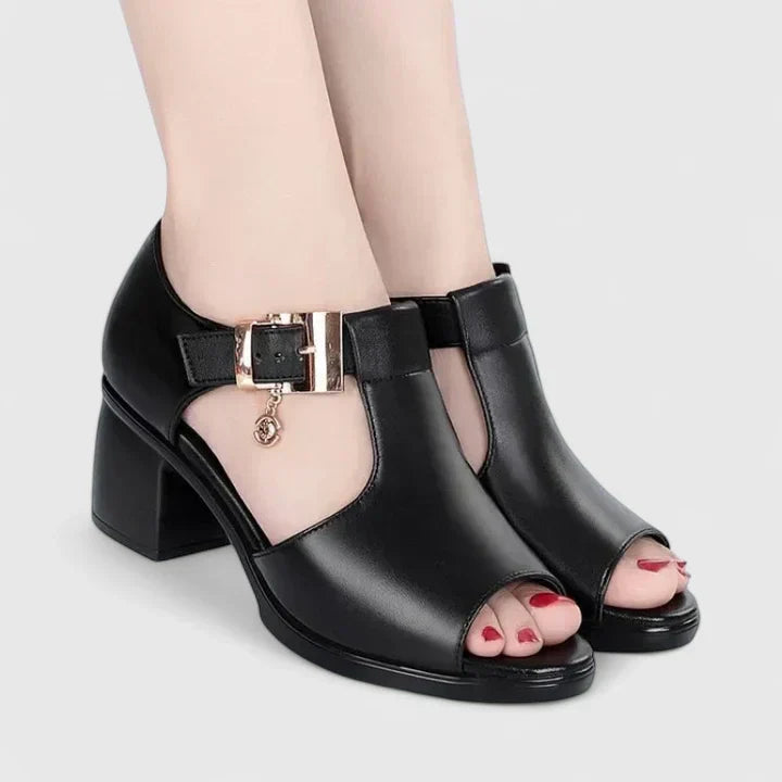 A woman wearing wine red elegant sandals with a broad, cushioned footbed.