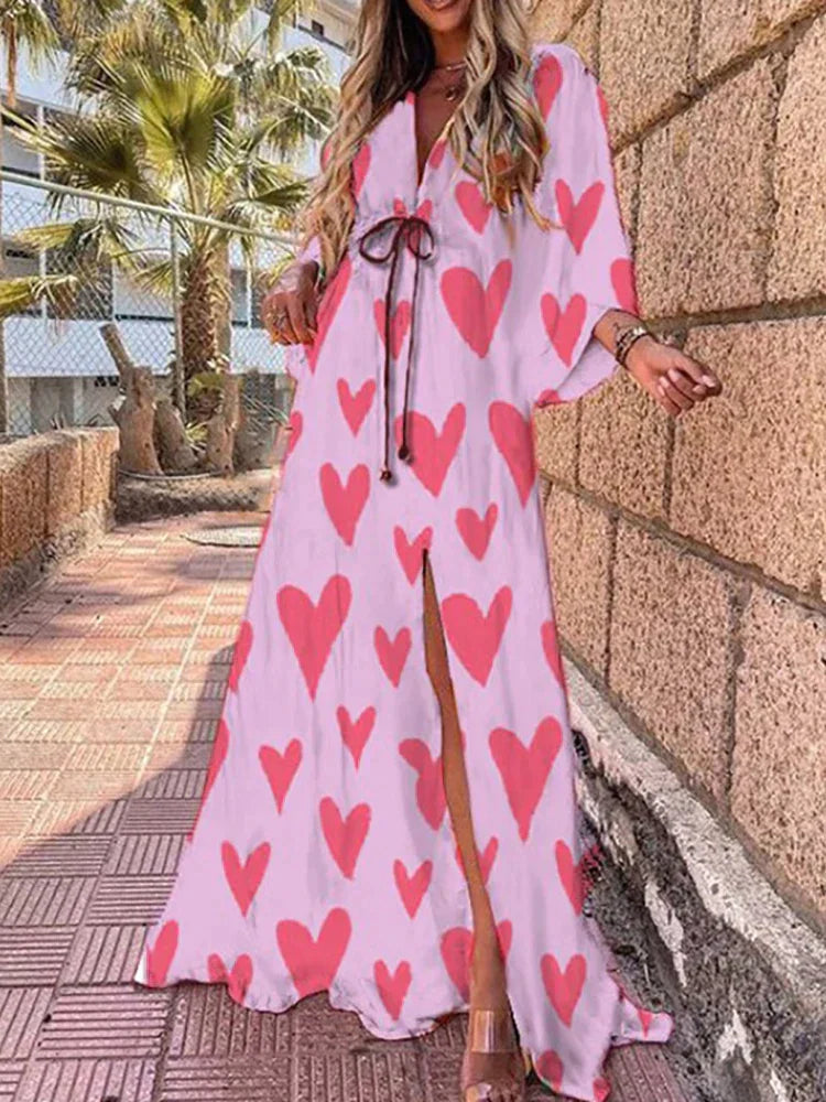 Woman wearing a colourful abstract print kaftan maxi dress with flowing sleeves by the water.