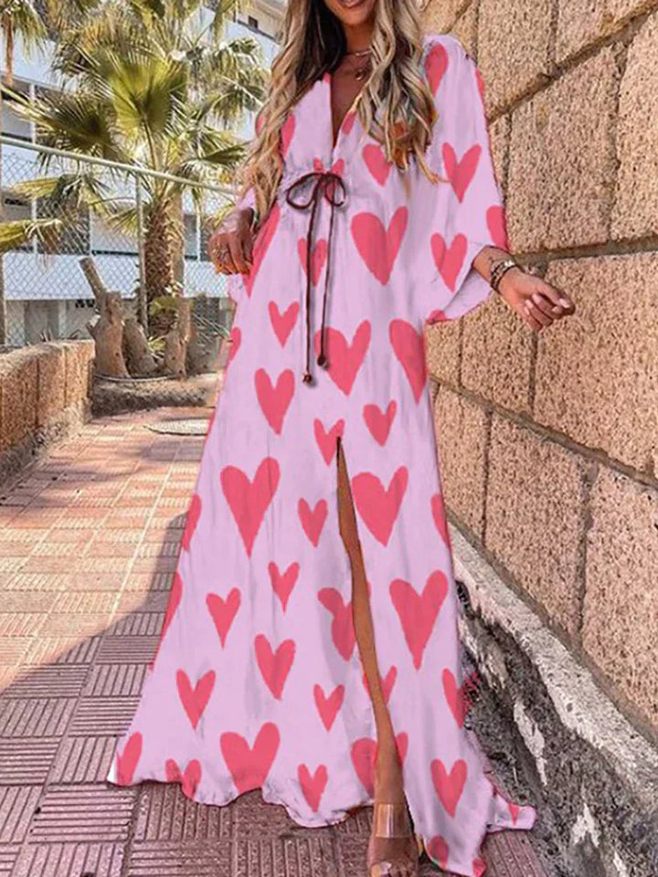 Woman wearing a colourful abstract print kaftan maxi dress with flowing sleeves by the water.