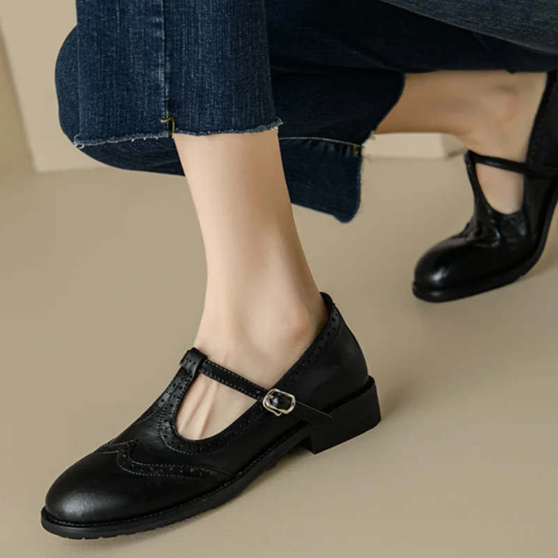 Brown and black Mary Jane shoes with brogue perforations and a T-bar buckle strap