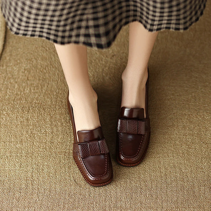 A woman wearing classic loafers with a subtle knot detail and tailored trousers