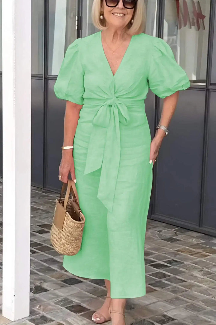Woman wearing the Bridget bow-front midi dress with puff sleeves at a garden party.