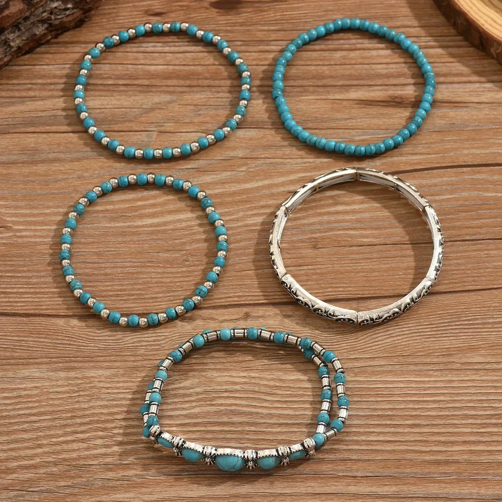Set of turquoise and metallic boho-style stacking bracelets on a white background