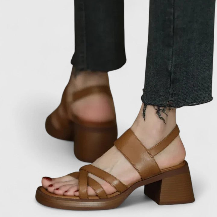 A woman wearing elegant cross-strap sandals with a summer dress, looking graceful and comfortable.