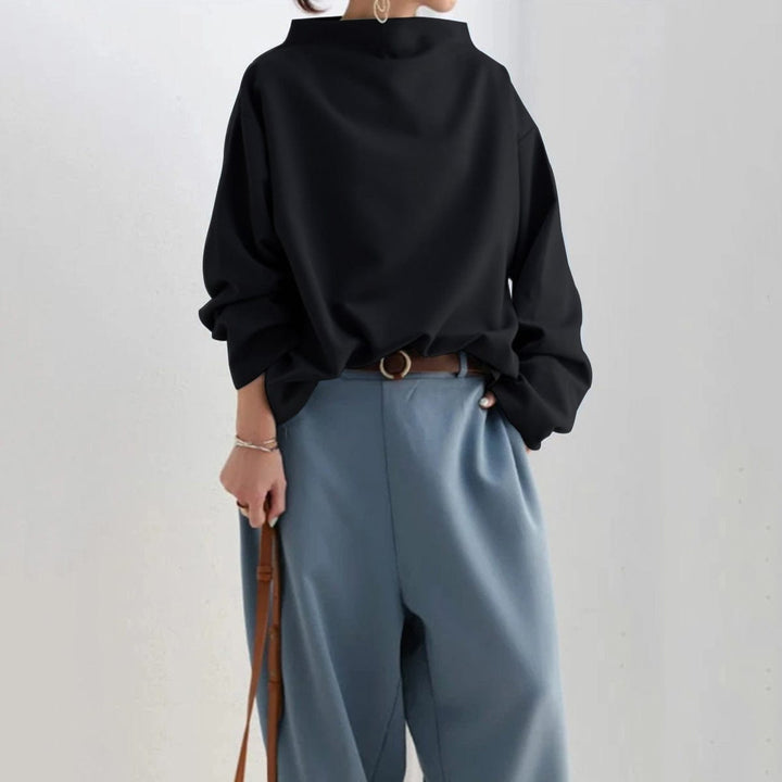 A woman wearing a soft funnel neck jumper styled with jeans for a relaxed elegant look.