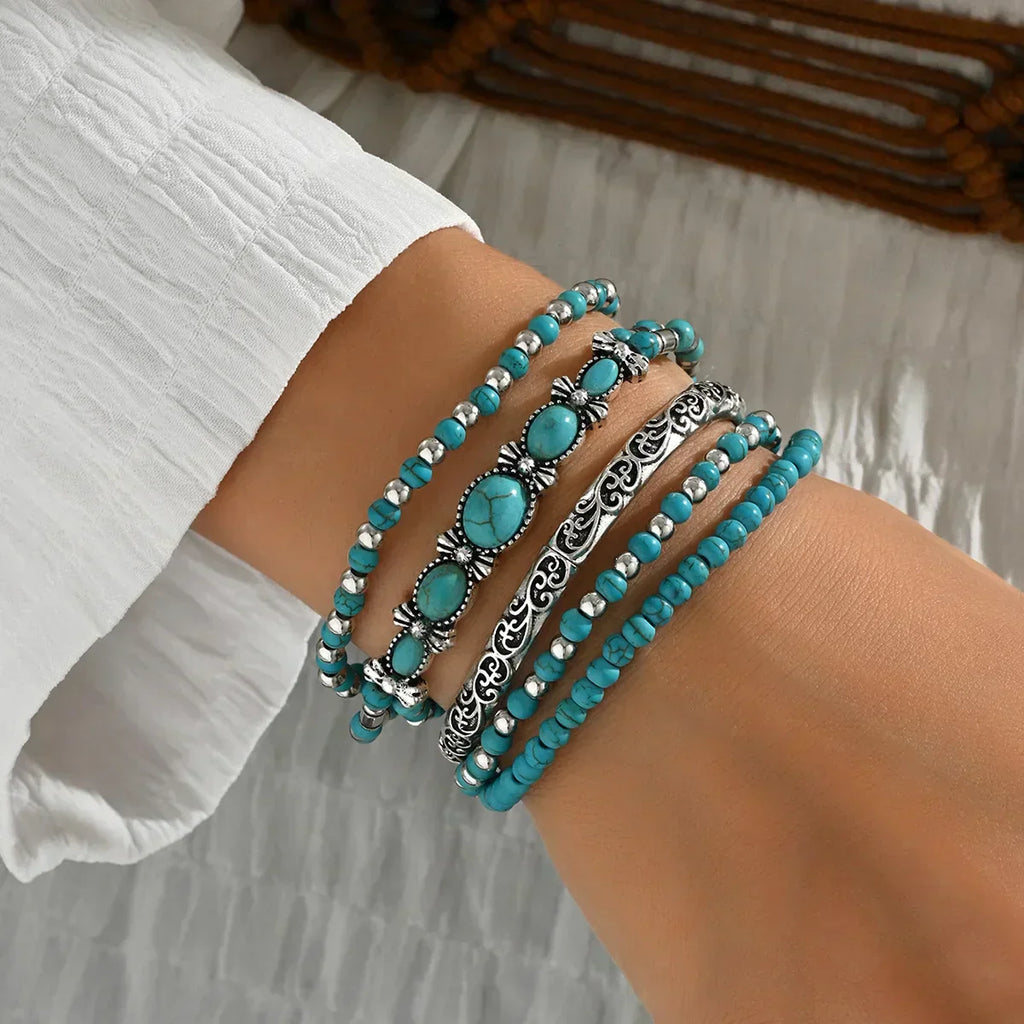 Set of turquoise and metallic boho-style stacking bracelets on a white background