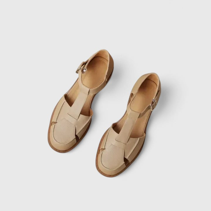 A woman wearing brown Mary Jane sandals with a T-strap and buckle, paired with a summer dress.