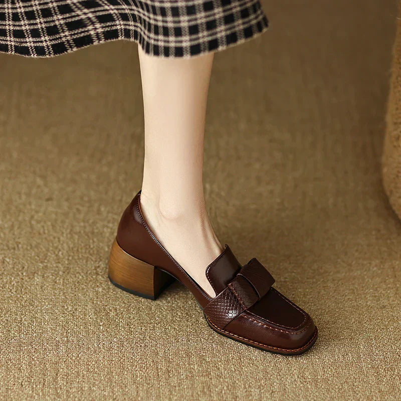 A woman wearing classic loafers with a subtle knot detail and tailored trousers