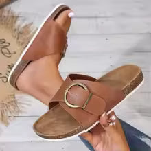 Black flat sandals with wide strap and decorative buckle detail