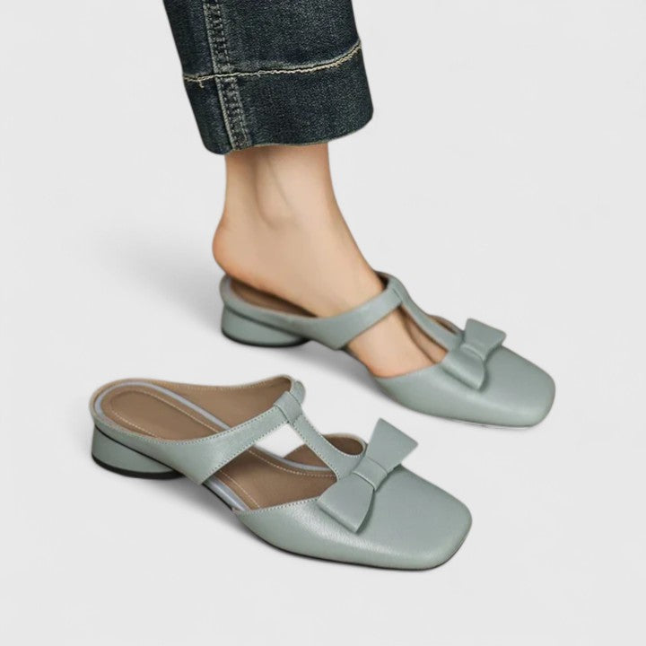 A woman wearing soft pink comfort sandals with a broad, cushioned footbed on a sunny day.