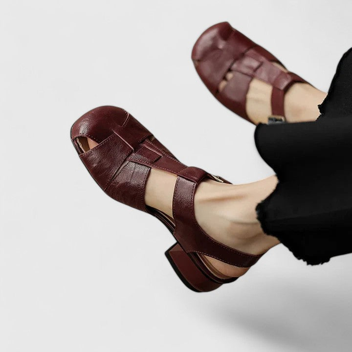 Black closed-toe sandals with a slim T-strap, buckled slingback and a low block heel.