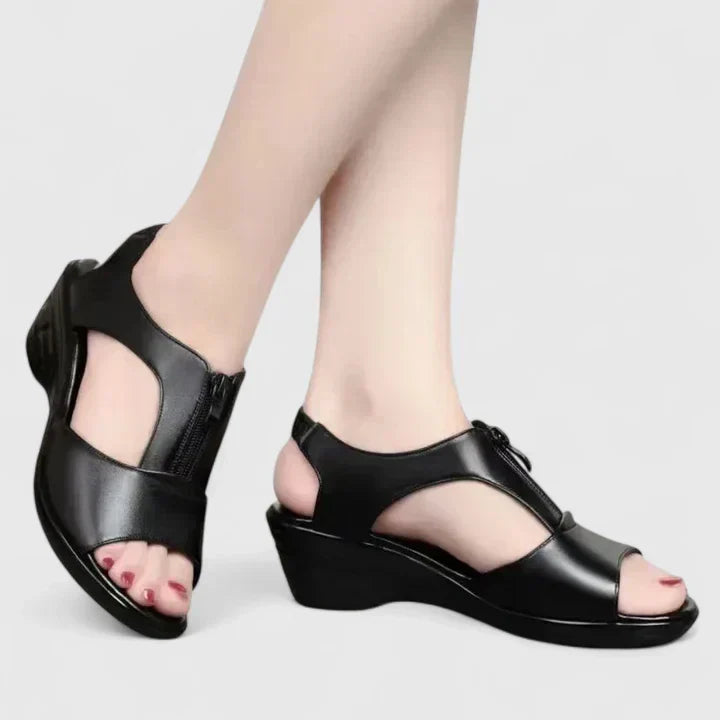 A woman wearing wine red elegant sandals with a broad, cushioned footbed.