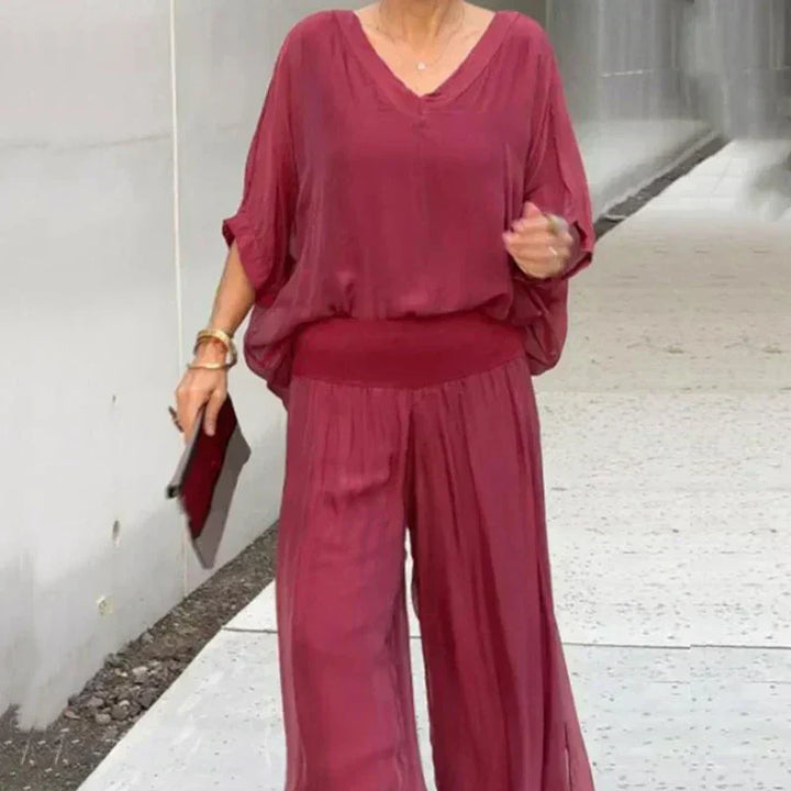 A woman wearing a flowing lounge two-piece set with a V-neck top and wide-leg trousers.