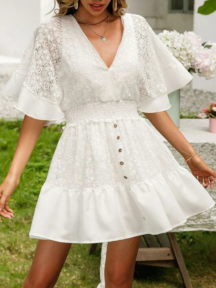 Woman in a delicately detailed boho mini dress with wide floaty sleeves at a garden party.