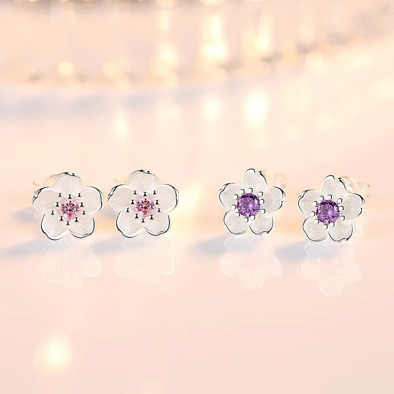 A pair of fine floral stud earrings in polished silver set with pink and purple zirconia stones