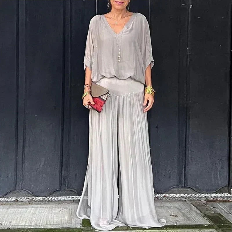 A woman wearing a flowing lounge two-piece set with a V-neck top and wide-leg trousers.